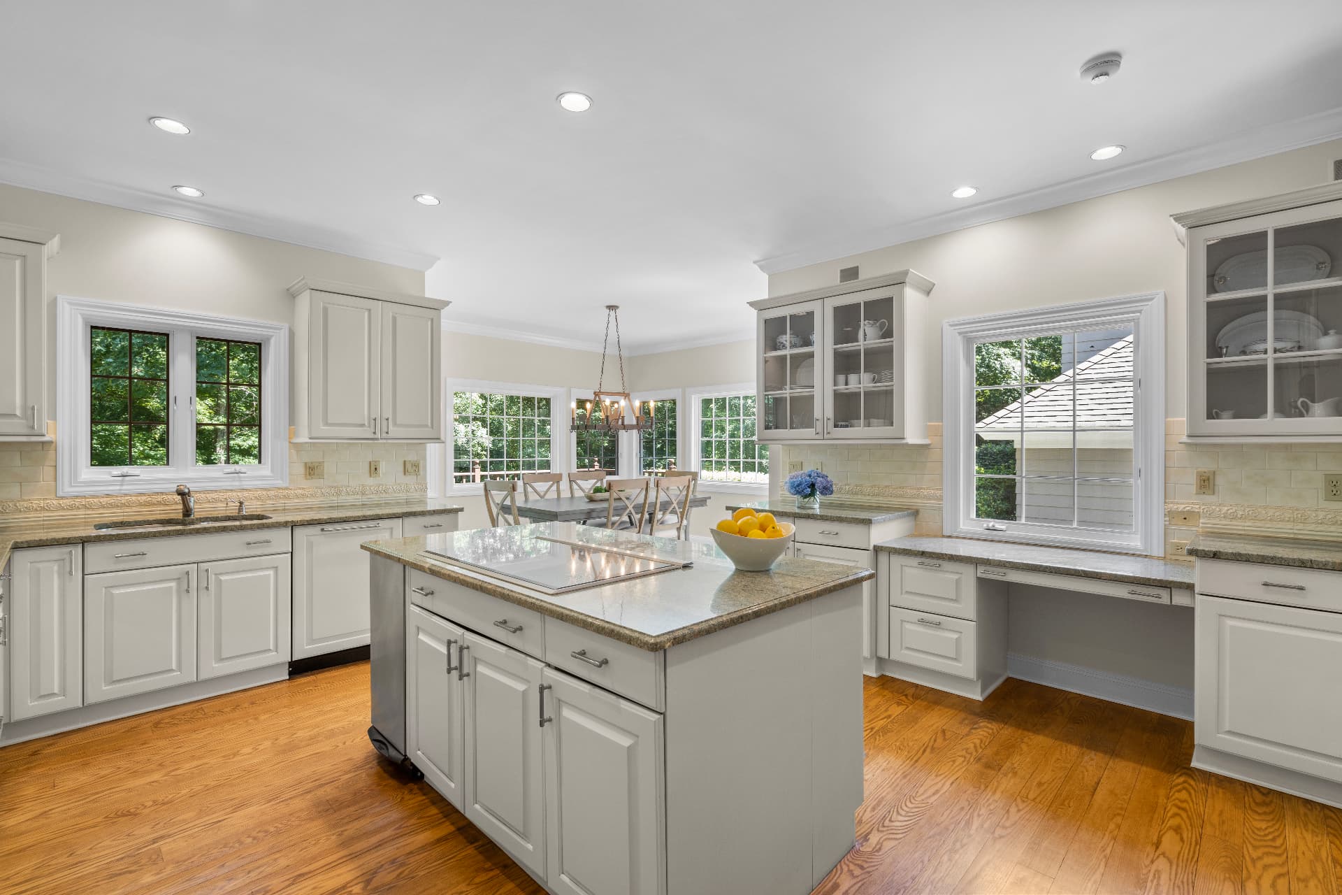 Cocina amplia con isla de granito y gabinetes blancos